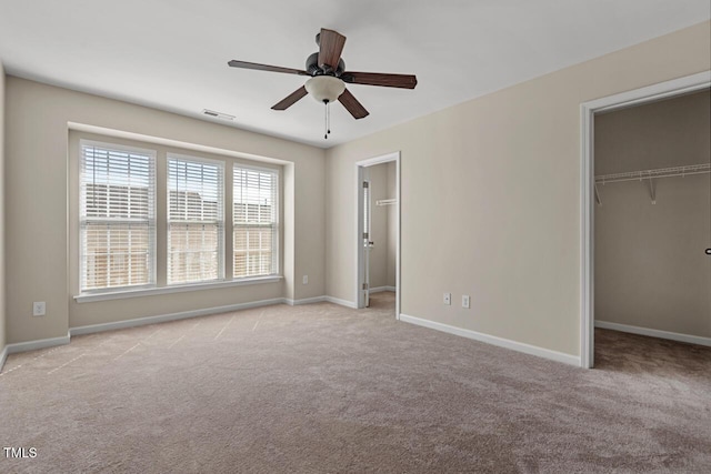 unfurnished bedroom featuring baseboards, visible vents, a walk in closet, and carpet