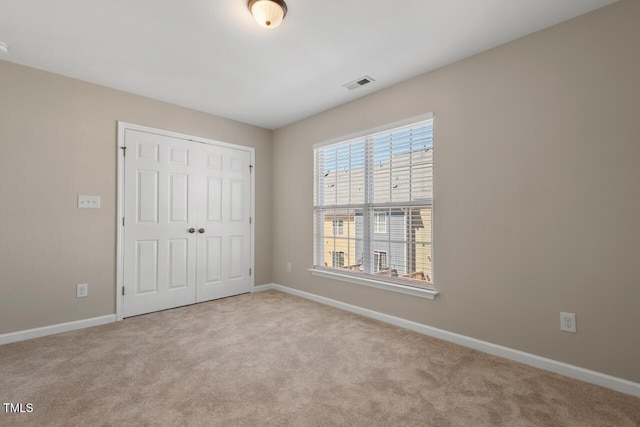 unfurnished bedroom featuring carpet floors, baseboards, visible vents, and a closet