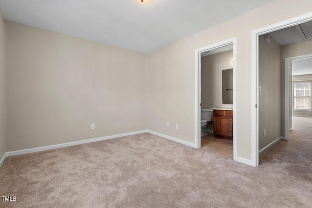 unfurnished bedroom with baseboards, attic access, and light carpet