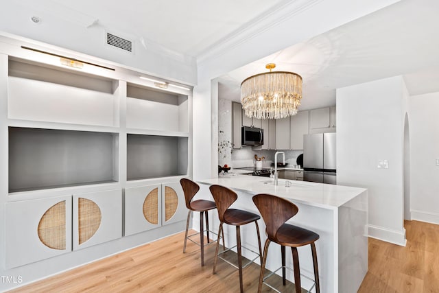 kitchen with light countertops, gray cabinetry, visible vents, a kitchen bar, and stainless steel appliances