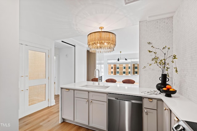 kitchen featuring stainless steel dishwasher, a peninsula, gray cabinets, a sink, and wallpapered walls