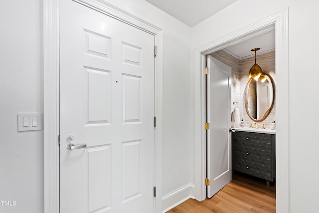 corridor with light wood-style flooring and a sink