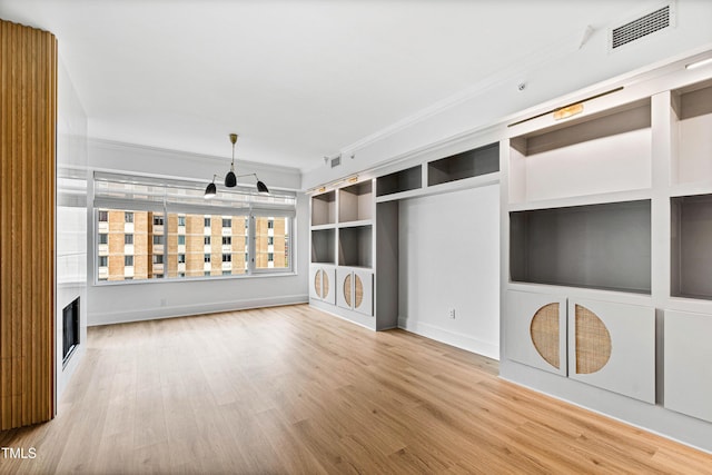 unfurnished living room with ornamental molding, visible vents, and wood finished floors