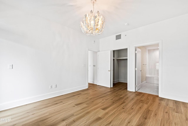 unfurnished bedroom with visible vents, baseboards, a chandelier, light wood-style floors, and connected bathroom