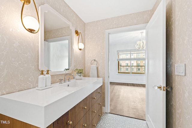 bathroom with baseboards, vanity, and wallpapered walls