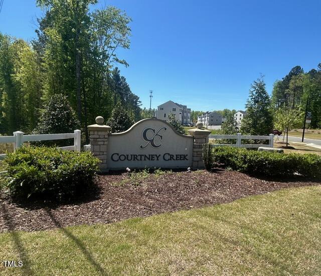 community sign with fence and a lawn