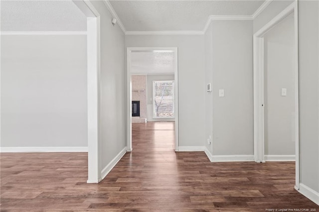 hallway with baseboards, a textured ceiling, wood finished floors, and crown molding