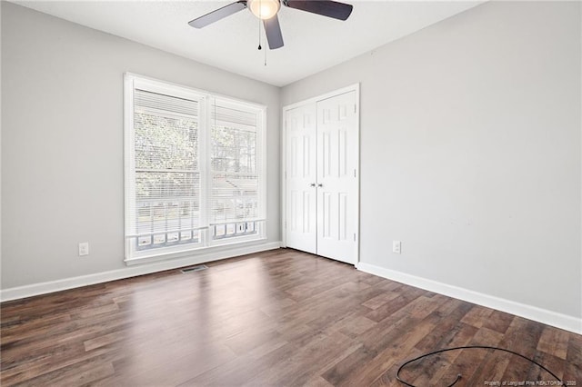 unfurnished bedroom featuring visible vents, a ceiling fan, wood finished floors, a closet, and baseboards