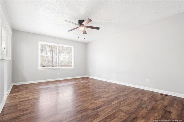 spare room featuring visible vents, dark wood-type flooring, a ceiling fan, and a textured ceiling