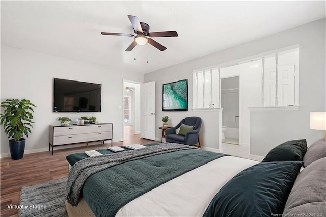 bedroom featuring a ceiling fan, ensuite bathroom, baseboards, and wood finished floors