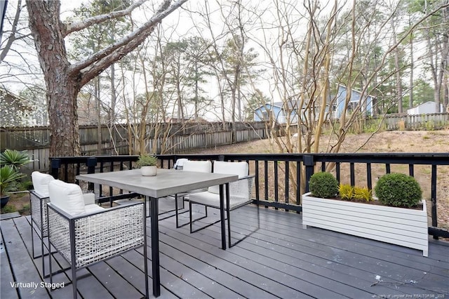 wooden terrace with outdoor dining space and a fenced backyard