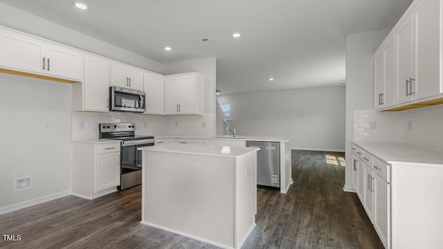 3040 Platinum Cir W, End, NC 27376 - kitchen with appliances with stainless steel finishes, a peninsula, decorative backsplash, dark wood-style flooring, and white cabinets