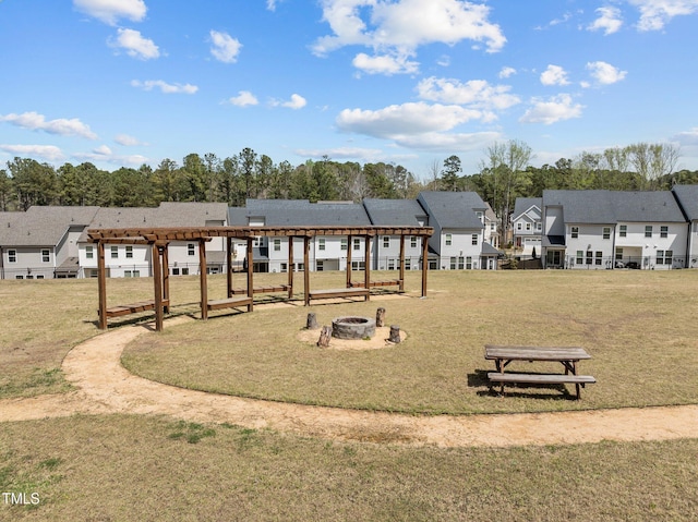 view of jungle gym featuring a pergola, a residential view, an outdoor fire pit, and a lawn