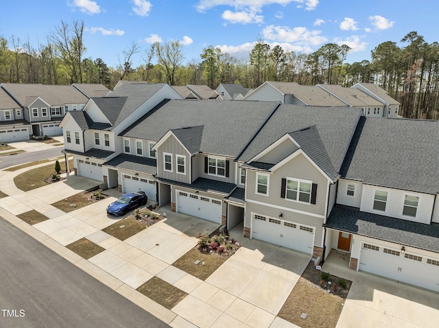 view of front facade with an attached garage, stone siding, board and batten siding, a residential view, and driveway