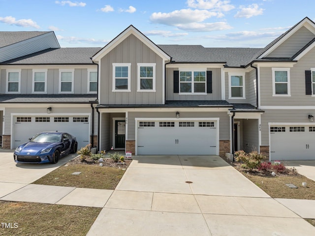 multi unit property with board and batten siding, driveway, stone siding, and a garage