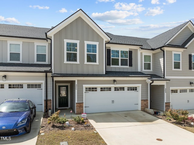 view of property with stone siding, a garage, board and batten siding, concrete driveway, and roof with shingles
