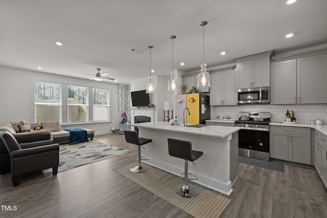 kitchen with tasteful backsplash, a breakfast bar, gray cabinets, open floor plan, and stainless steel appliances