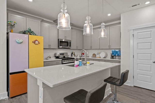 kitchen featuring tasteful backsplash, gray cabinets, a sink, and appliances with stainless steel finishes