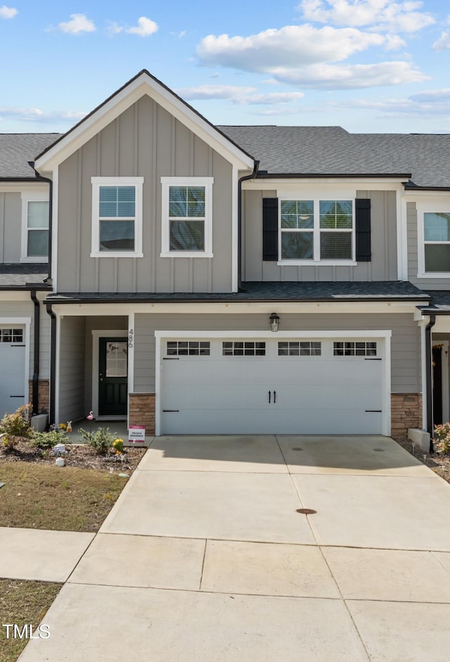 view of front of house with a garage, board and batten siding, stone siding, and concrete driveway