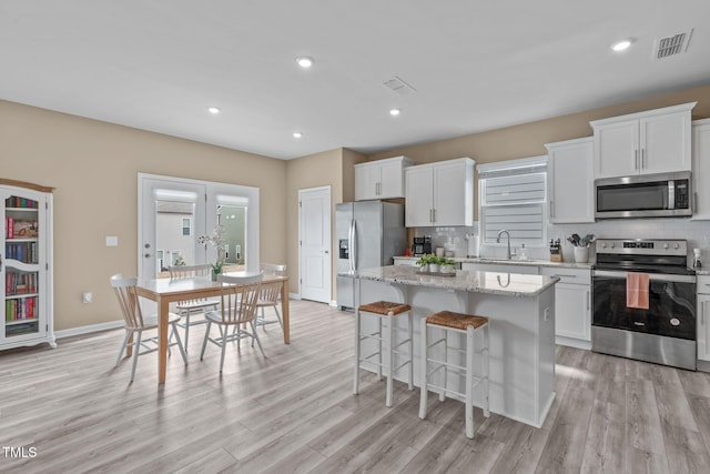 656 Dallas Rose Dr, Wendell, NC 27591 - kitchen featuring tasteful backsplash, a center island, white cabinets, and stainless steel appliances