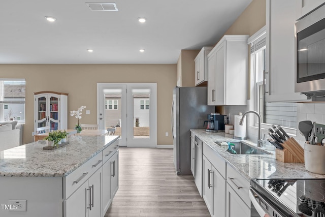 656 Dallas Rose Dr, Wendell, NC 27591 - kitchen with white cabinets, visible vents, a center island, a sink, and stainless steel appliances