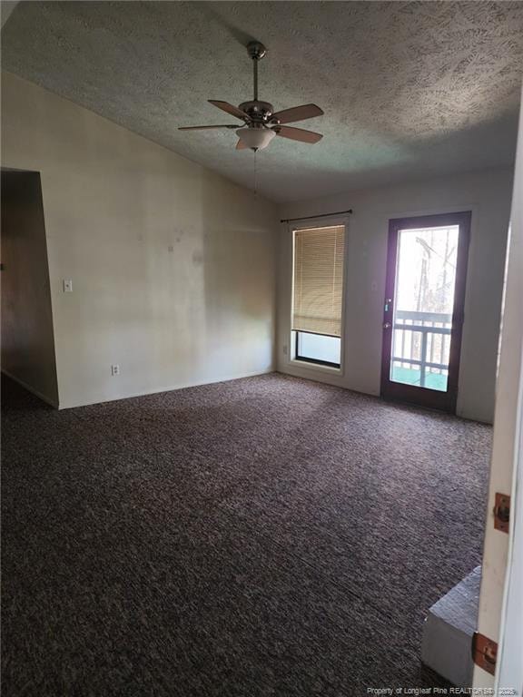 carpeted spare room featuring vaulted ceiling, a ceiling fan, and a textured ceiling