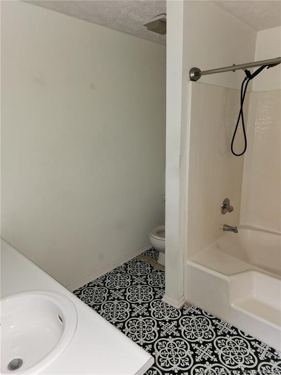 full bathroom with toilet, a sink, a textured ceiling, tile patterned flooring, and shower / bathtub combination