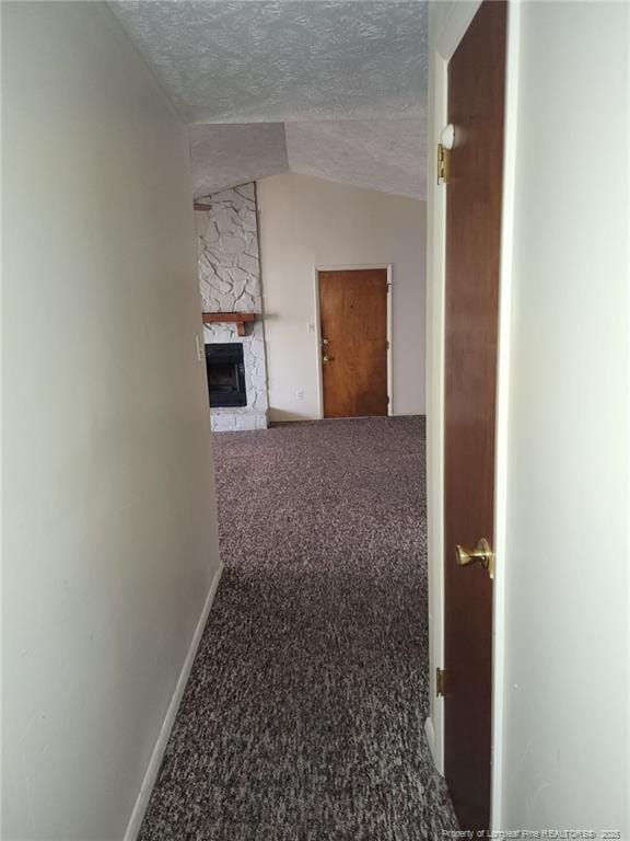 hall with baseboards, carpet floors, a textured ceiling, and vaulted ceiling