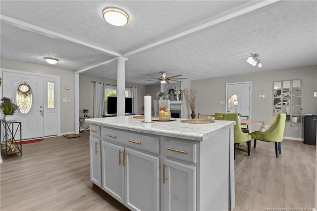 kitchen featuring light wood finished floors, a ceiling fan, a textured ceiling, a kitchen island, and light countertops