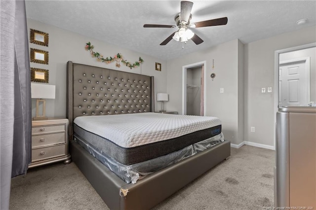 carpeted bedroom with baseboards, ceiling fan, a closet, a textured ceiling, and a walk in closet