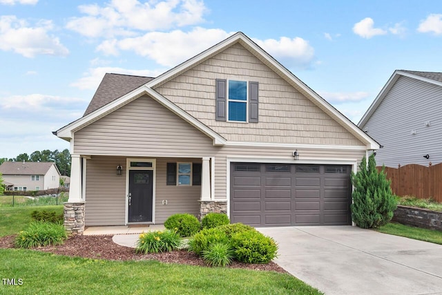 view of front of property with a garage, a porch, driveway, fence, and stone siding
