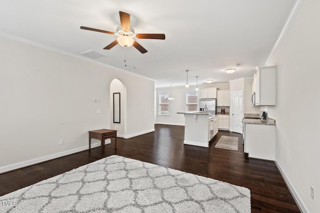unfurnished bedroom with crown molding, stainless steel fridge with ice dispenser, dark wood finished floors, baseboards, and arched walkways