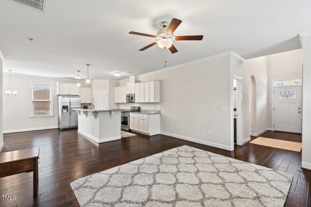 kitchen featuring appliances with stainless steel finishes, a kitchen breakfast bar, a ceiling fan, baseboards, and ornamental molding