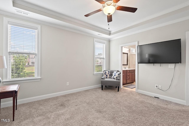 sitting room with crown molding, a tray ceiling, light carpet, baseboards, and ceiling fan