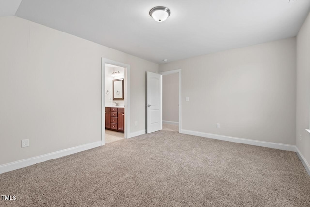 unfurnished bedroom with light colored carpet, baseboards, and ensuite bath