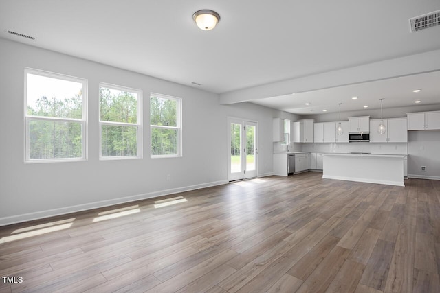 unfurnished living room featuring baseboards, visible vents, wood finished floors, and recessed lighting