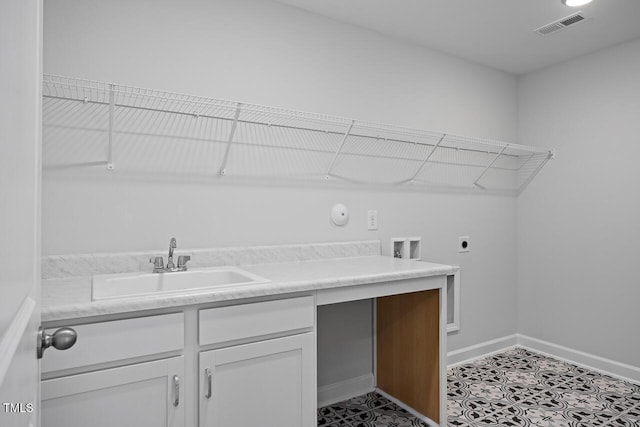 laundry room with a sink, electric dryer hookup, visible vents, baseboards, and cabinet space