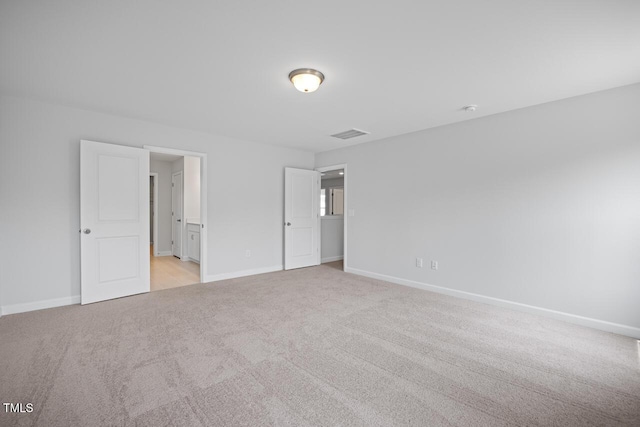 unfurnished bedroom with connected bathroom, visible vents, light carpet, and baseboards