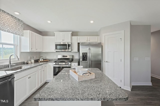 kitchen featuring a sink, light stone counters, recessed lighting, stainless steel appliances, and white cabinets