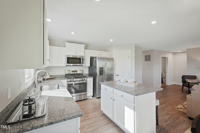 kitchen featuring light wood-type flooring, visible vents, a sink, a kitchen island, and stainless steel appliances