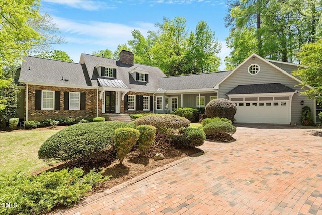 view of front of house featuring a garage, a chimney, decorative driveway, and brick siding
