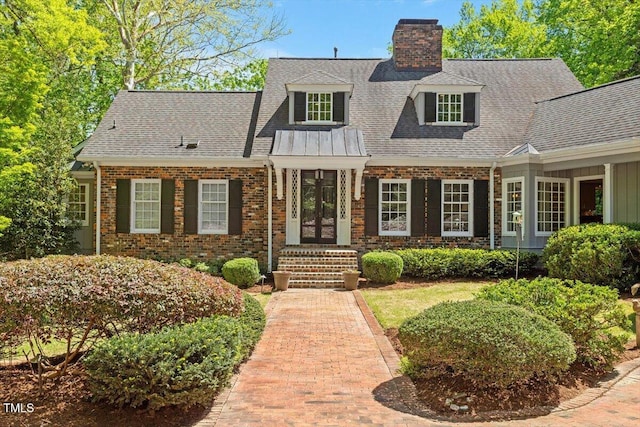 view of front of property featuring a chimney, roof with shingles, and brick siding