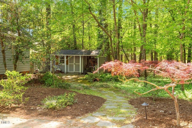 view of yard featuring a storage unit, an outbuilding, and a view of trees
