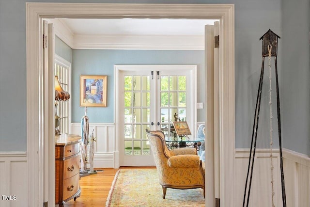 office space with wood finished floors, a wainscoted wall, a decorative wall, french doors, and crown molding