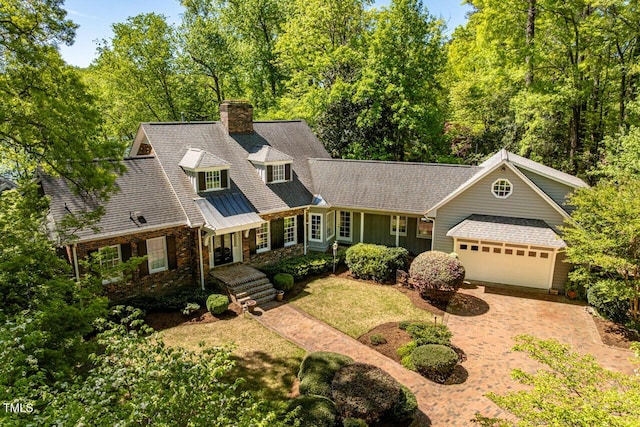shingle-style home featuring an attached garage, driveway, and a chimney
