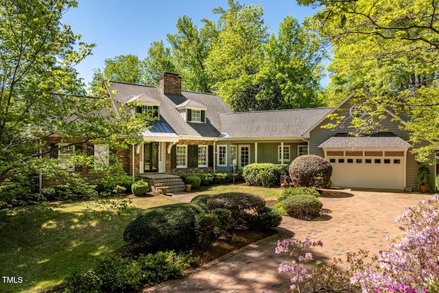 view of front of property featuring a garage, a chimney, decorative driveway, and a front lawn