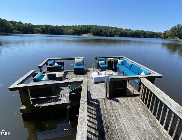 dock area with a water view, outdoor lounge area, and a view of trees