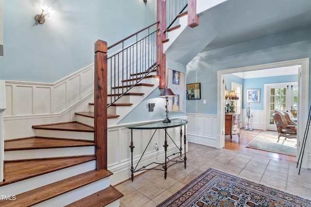 staircase with a decorative wall, a wainscoted wall, and tile patterned flooring