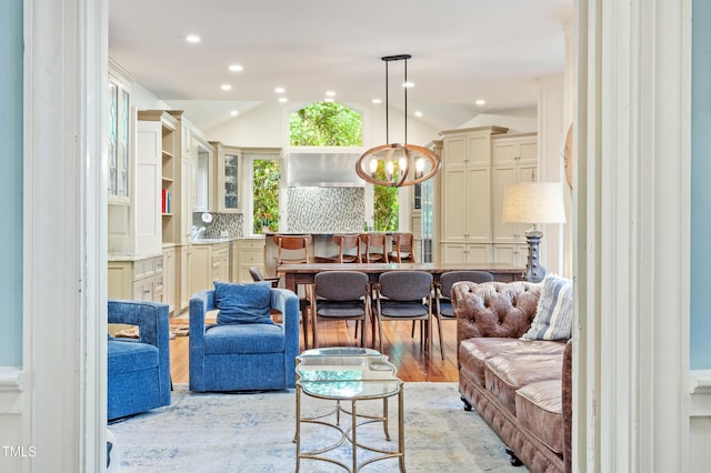 living room with lofted ceiling, a chandelier, light wood-style flooring, and recessed lighting