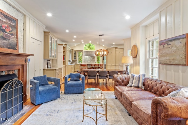 living area with light wood-type flooring, a chandelier, recessed lighting, a fireplace, and lofted ceiling